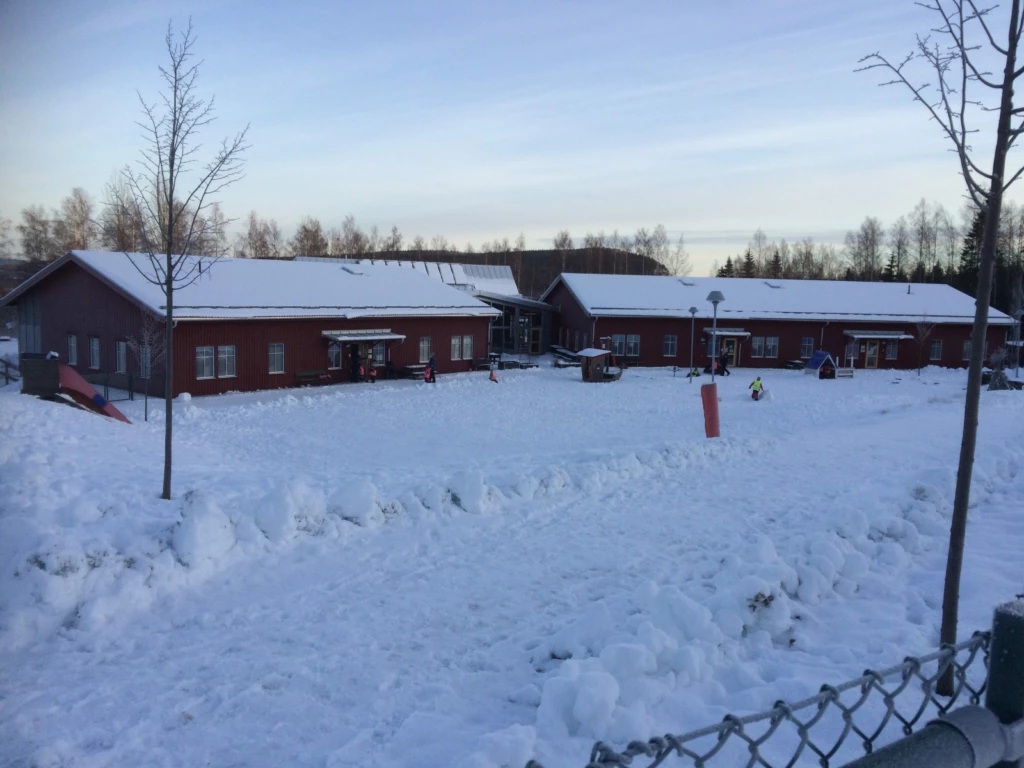 Röda byggnader med staket i snö
