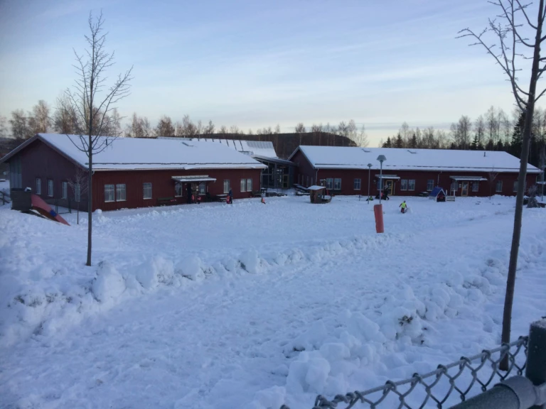 Röda byggnader med staket i snö