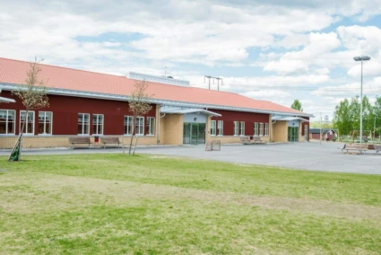 Enbacka skolas röda byggnad sett snett framifrån.