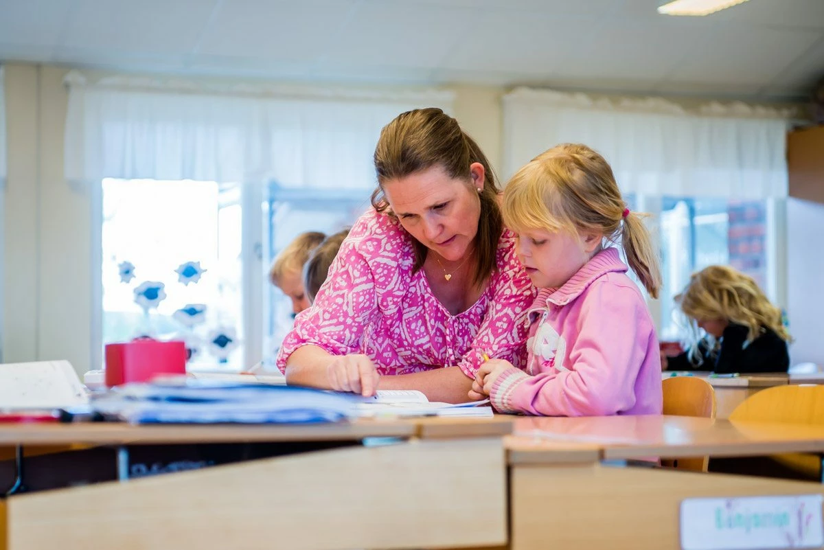 En lärare hjälper en elev i klassrummet.