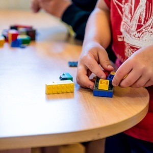 Närbild på ett barns händer som bygger med lego.
