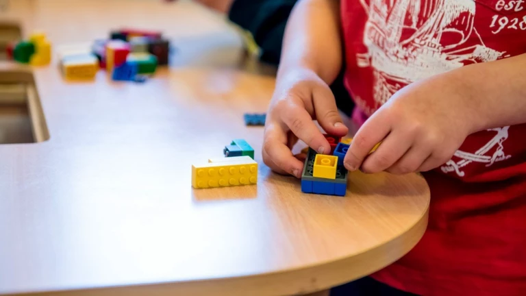 Närbild på ett barns händer som bygger med lego.