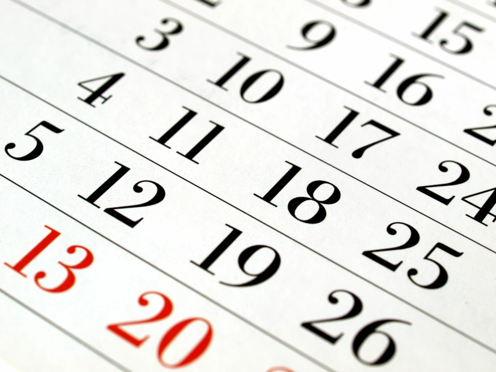 Närbild på kalender med svarta och röda dagar.