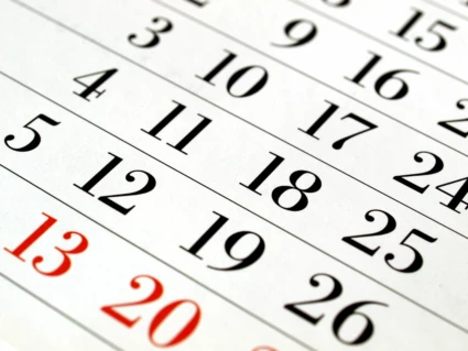 Närbild på kalender med svarta och röda dagar.
