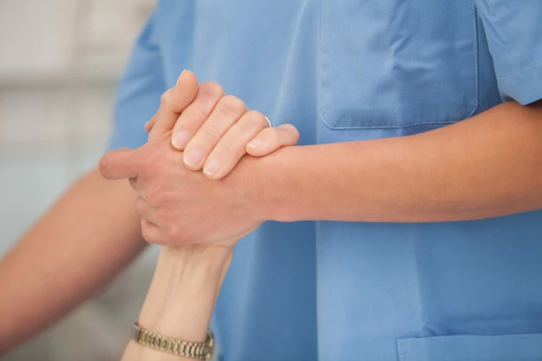 En sköterska håller handen på en patient.