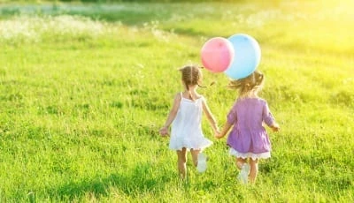 Två barn som håller hand och håller 2 ballonger