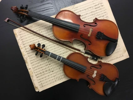 På ett svart bord ligger det notpapper och på noterna ligger även två stycken fioler.
