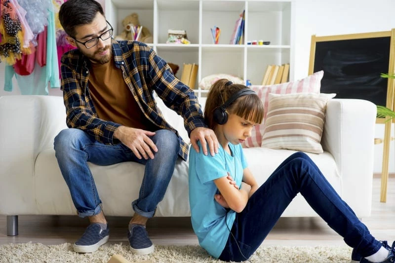 förälder lägger handen på axeln på butter tonåring.