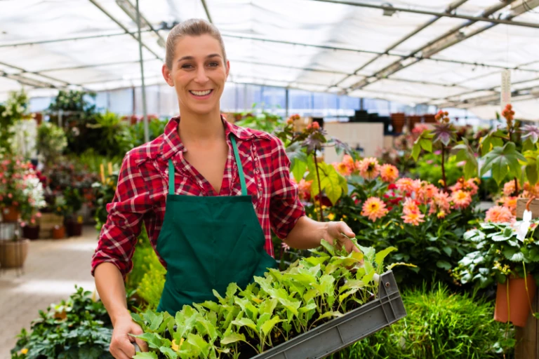 kvinna i växthus med blomkruka i handen