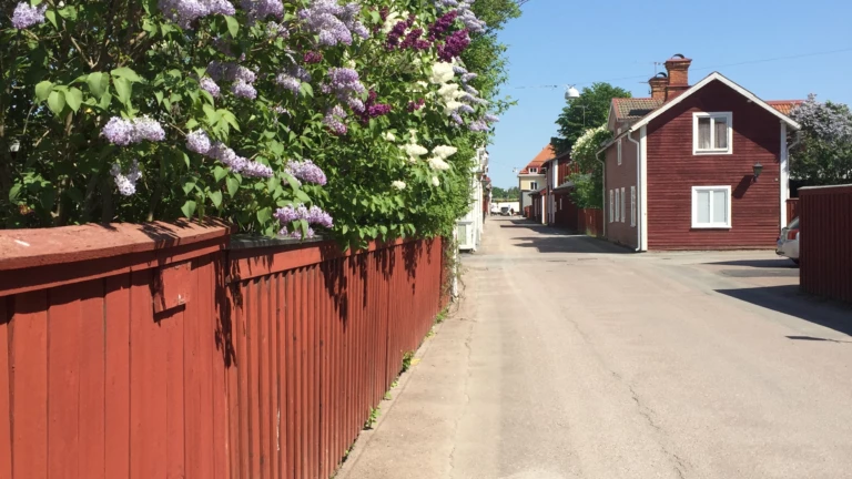 En gata med ett rött plank och äldre hus.