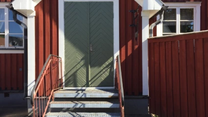 En äldre veranda på ett rött hus.