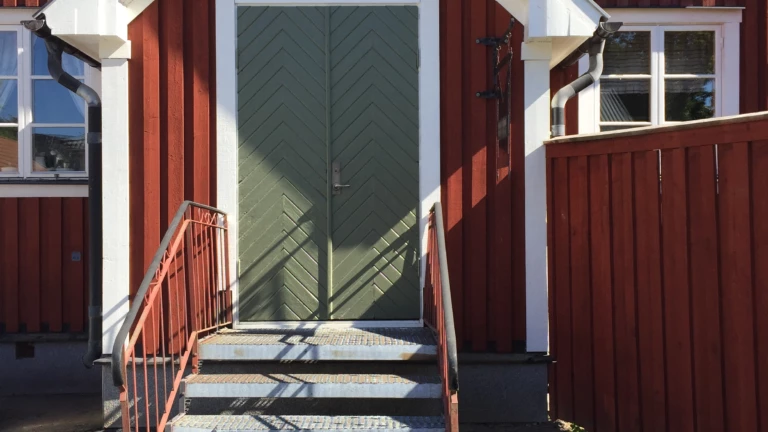 En äldre veranda på ett rött hus.