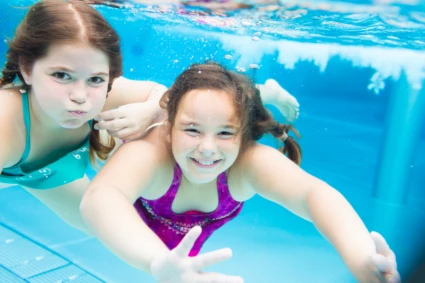 Två flickor simmar i en pool.