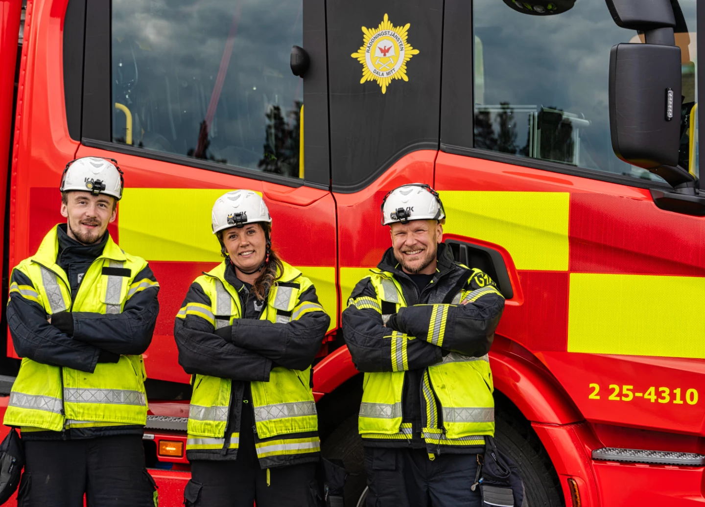 Tre brandmän som står framför en brandbil