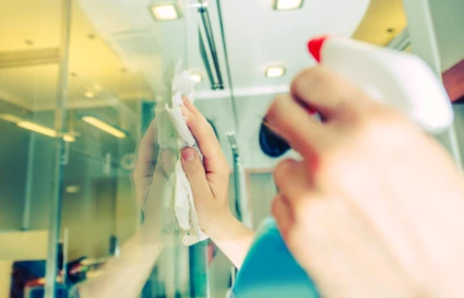 Närbild när en person putsar en glasruta med fönsterputs