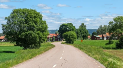 En landsväg bredvid åkrar och röda hus