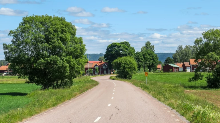 En landsväg bredvid åkrar och röda hus