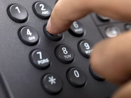 En människas fingrar trycker ner knappar på en telefon