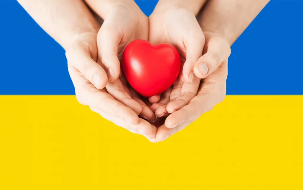 ukrainska flaggan som bakgrund till två händer som håller ett hjärta.