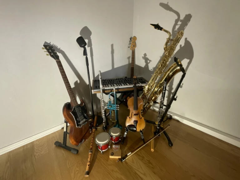 En mångfald av olika musikinstrument placerade i ett hörn av ett rum.