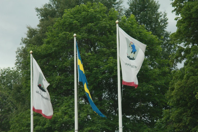 Tre flaggor upphissade på flaggstänger