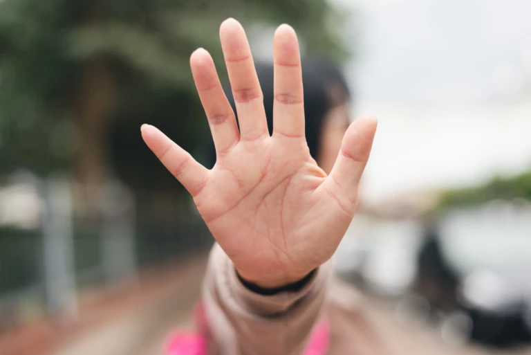 Kvinna visar stopptecken med sin hand.
