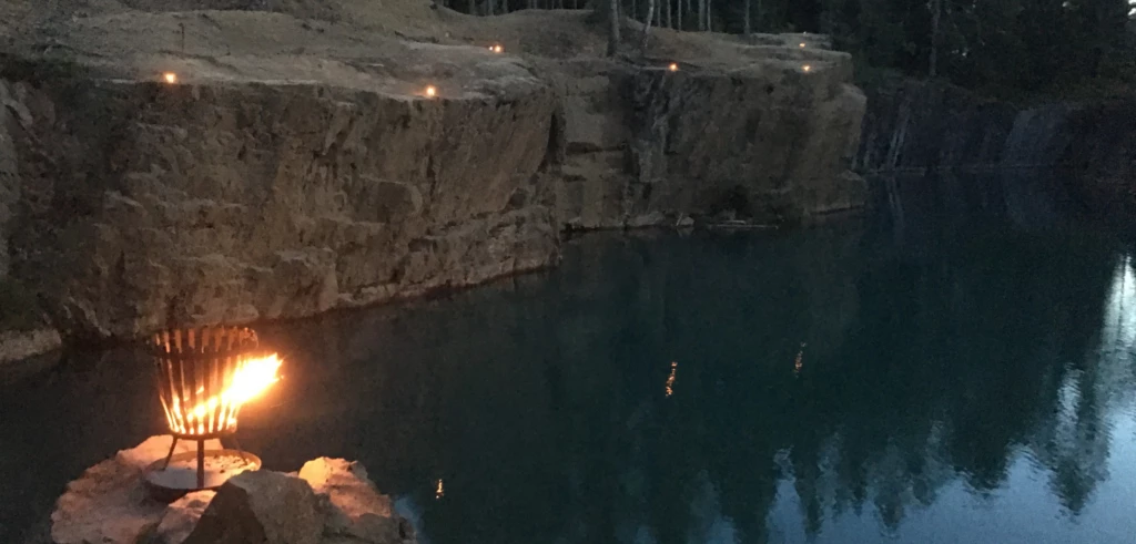 Naturbild över östra Silvbergs gruva i skymningen, Eldar brinner vid vattnet