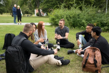 Några ungdomar sitter i en ring på gräset utanför campus.