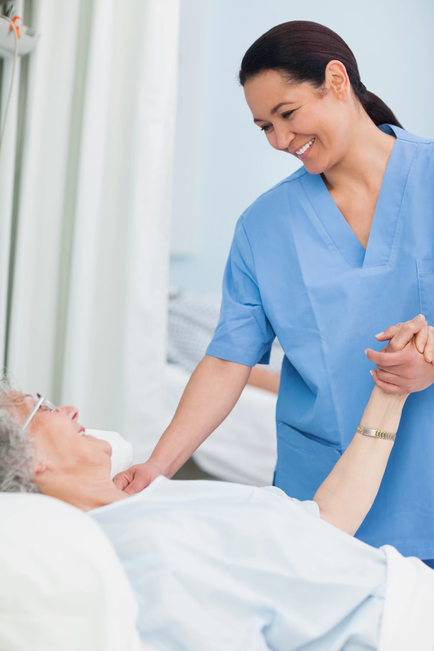 En sjuksköterska håller en patient i handen.