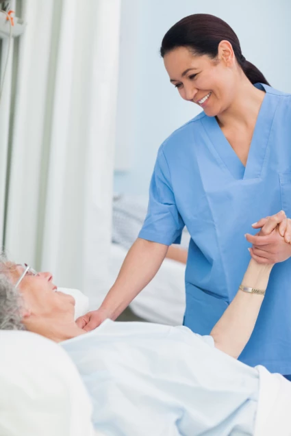 En sjuksköterska håller en patient i handen.