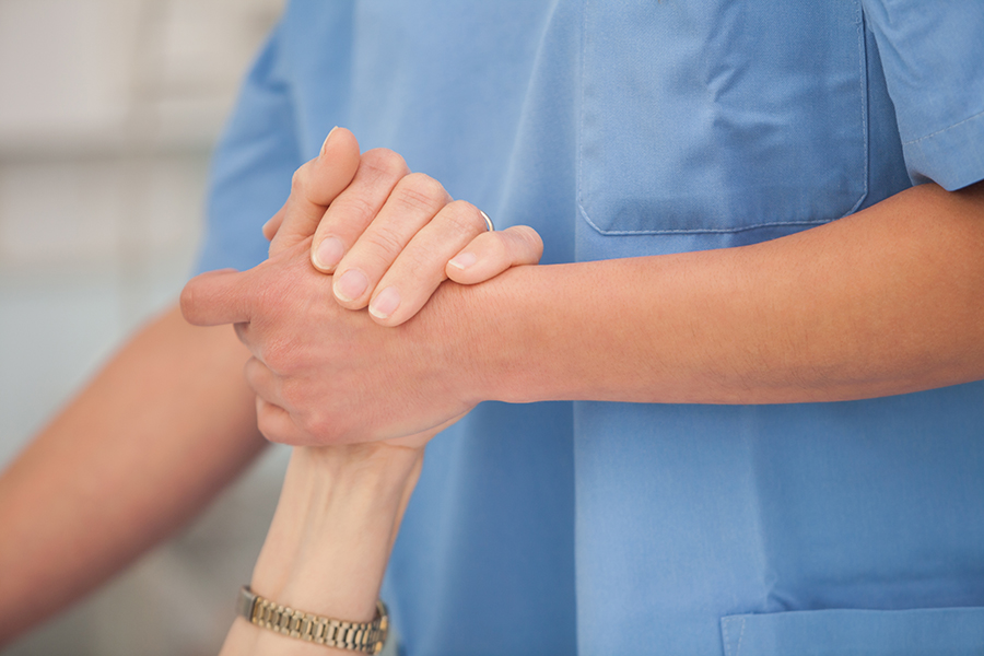 En sköterska håller handen med en äldre kvinna