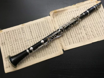 Klarinett som ligger ovanpå notblad på en svart bakgrund.