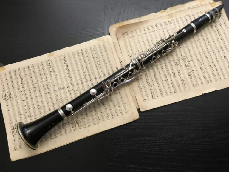 Klarinett som ligger ovanpå notblad på en svart bakgrund.