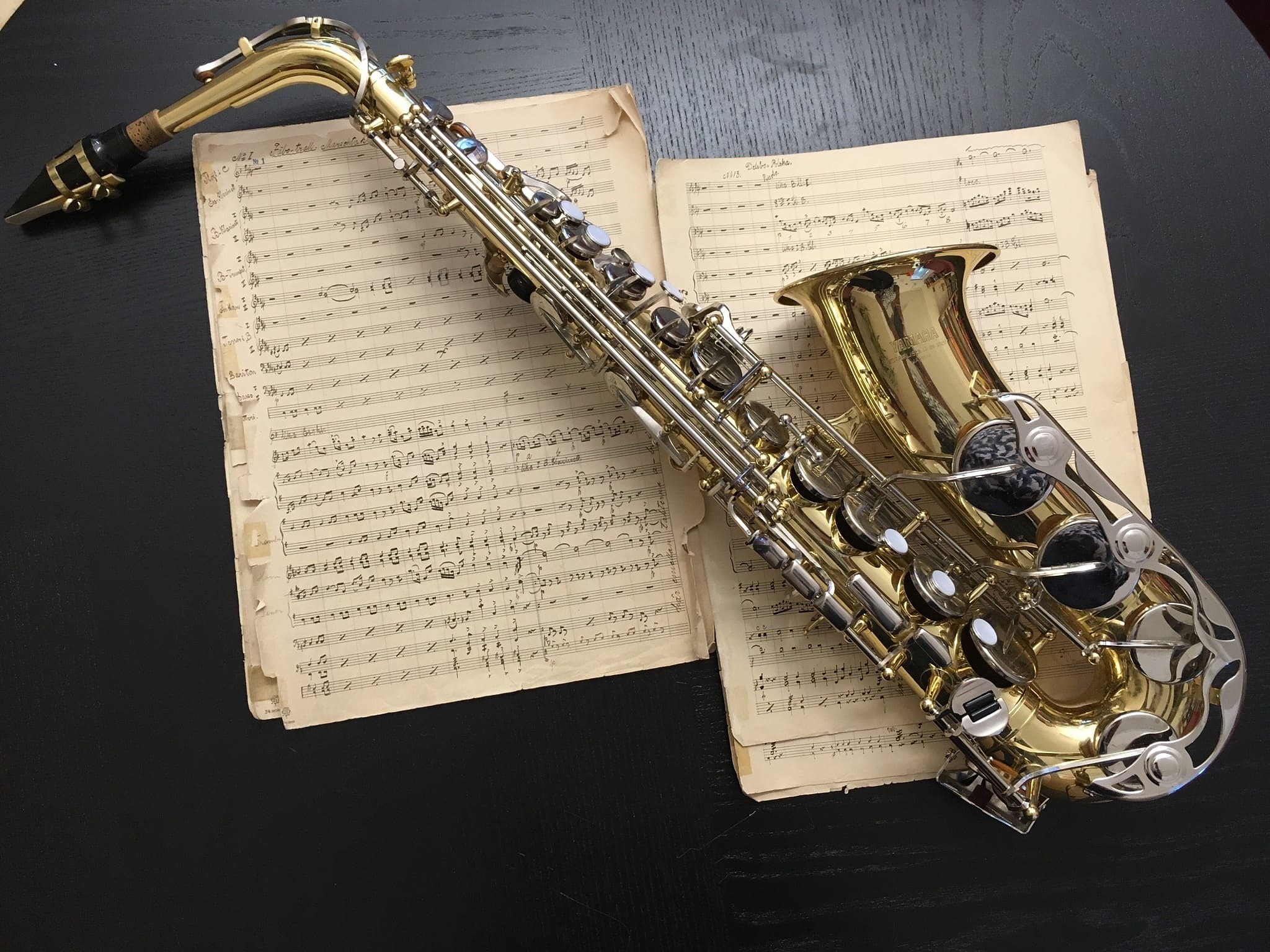 Bilden föreställer en Saxofon som ligger på ett par notblad.