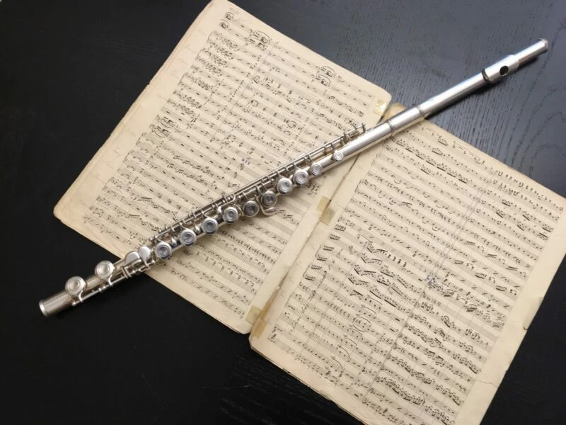En tvärflöjt som ligger ovanpå ett uppslag med notblad.