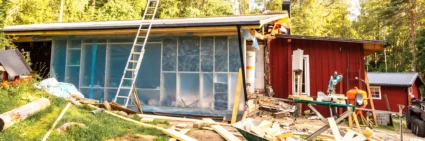 Ombyggnation av ett rött lågt hus där det ligger brädor på backen