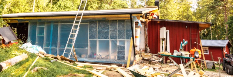 Ombyggnation av ett rött lågt hus där det ligger brädor på backen
