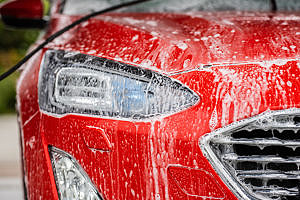 En röd bil som tvättas i en biltvätt.