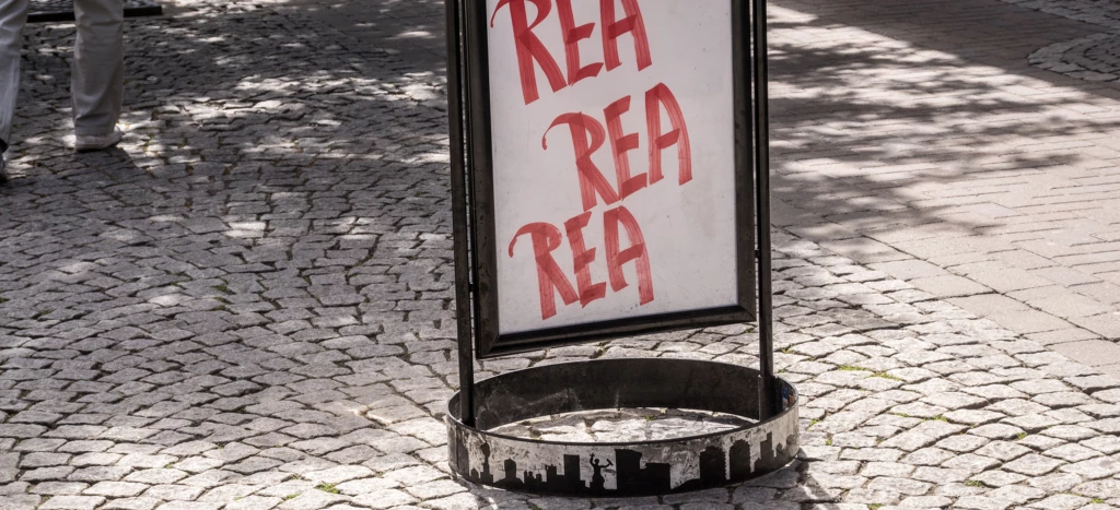 Gatupratare med texten rea, som står på en kullerstensgata