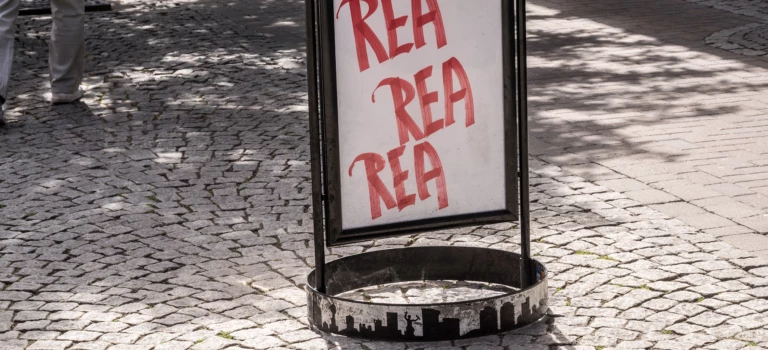 Gatupratare med texten rea, som står på en kullerstensgata