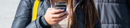 Kvinna pratar i mobiltelefon med hörlurar