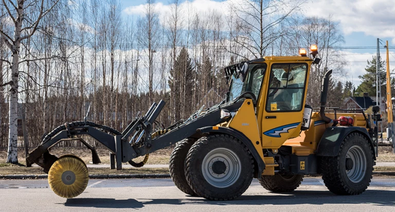 En traktor som sopar upp grus på gatan