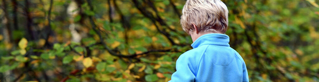 Ett barn med blå jacka i skogen