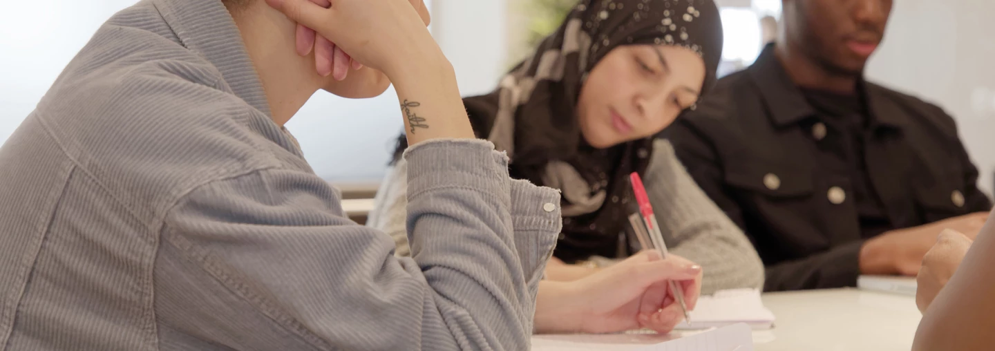 Elever pluggar i klassrum under vuxenutbildning Svenska för invandrare med mixad etnicitet