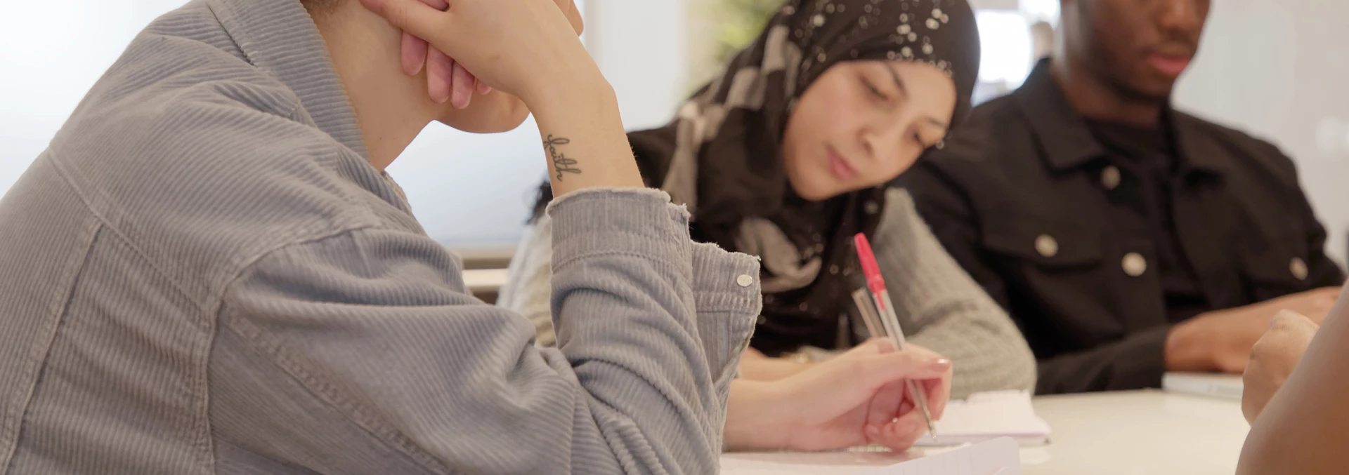 Elever pluggar i klassrum under vuxenutbildning Svenska för invandrare med mixad etnicitet