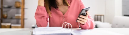 En kvinna med mobiltelefon och pärm med papper