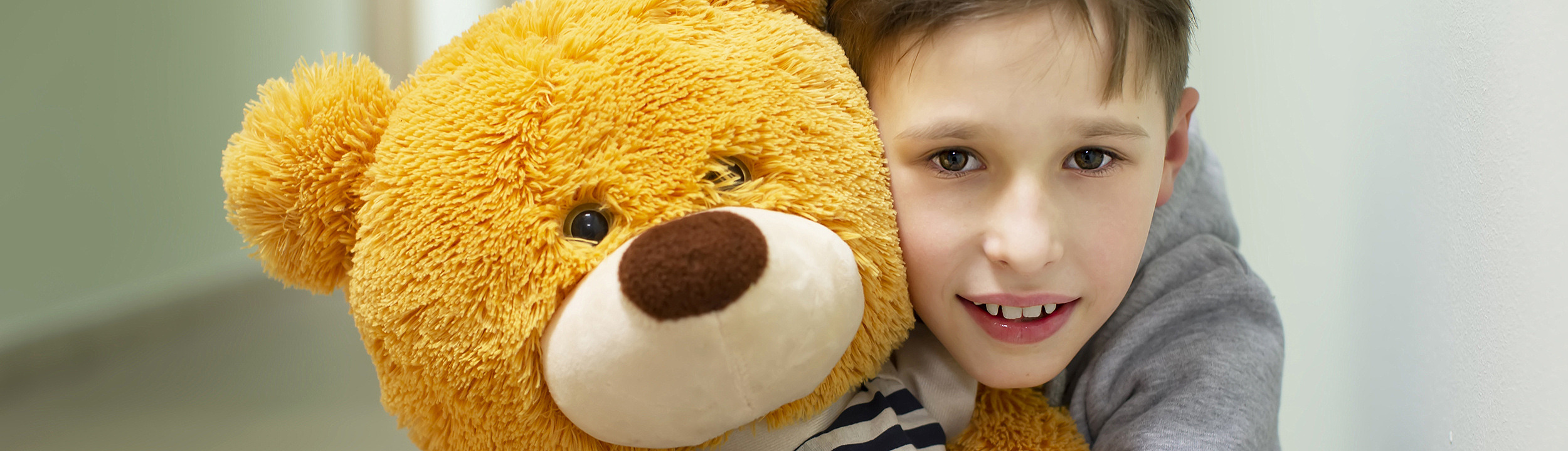 En pojke som kramar en gul nallebjörn
