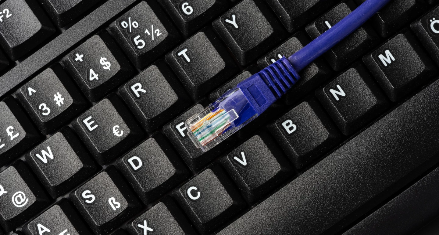 En datakabel som ligger på ett svart tangentbord