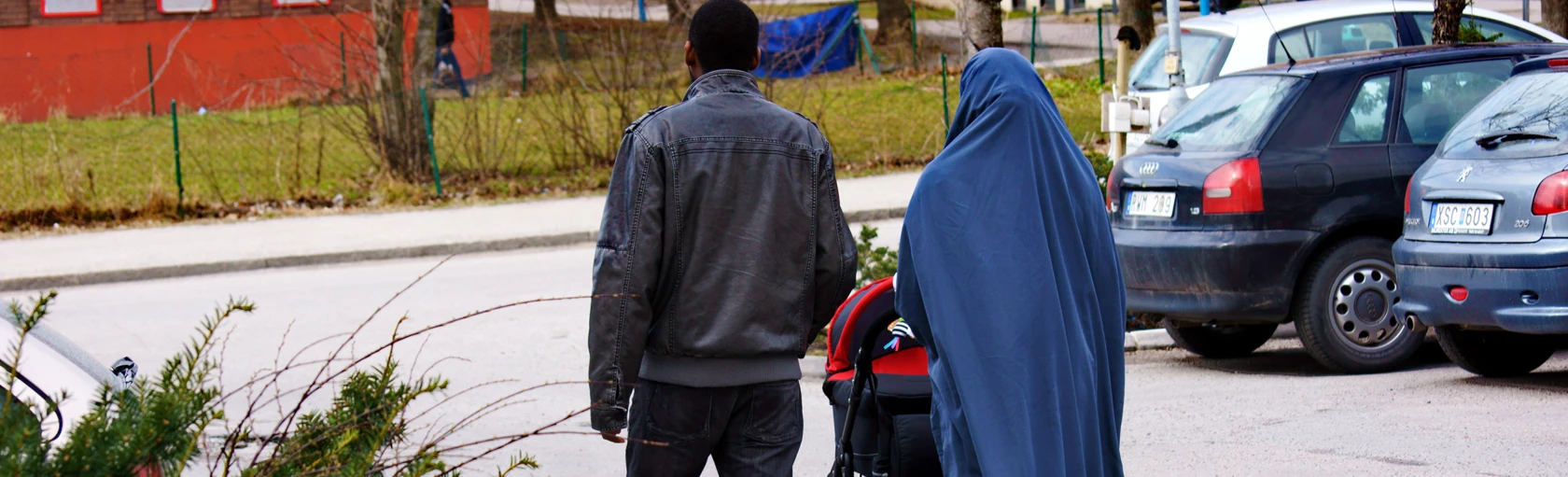 En man och en kvinna bakifrån går med en barnvagn