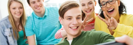 Flera ungdomar tittar in i en skärm och ler